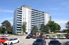 St. Catharines apartment for rent - A parking lot with cars and a large white building in the background.