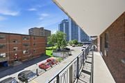 Hamilton apartment for rent - A balcony with a black railing overlooks a parking lot and a street.