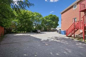 Kitchener apartment for rent - A parking lot with a red building and trees in the background.