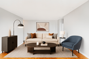 Stoney Creek apartment for rent - A living room with a white couch, a brown coffee table, a blue armchair, and a brown cabinet.