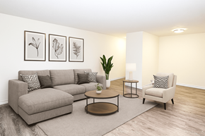 Kitchener apartment for rent - A living room with a grey sofa, a coffee table, a chair, and three framed pictures on the wall.