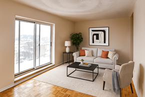 Hamilton apartment for rent - A living room with a white couch, a coffee table, and a large window.