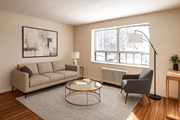 Hamilton apartment for rent - A living room with a beige couch, a grey armchair, a glass coffee table, and a framed artwork on the wall.
