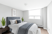 Hamilton apartment for rent - A bedroom with a bed, pillows, a blanket, a nightstand, and a window.