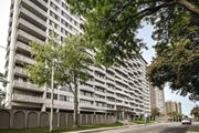 Hamilton apartment for rent - A tall residential building with balconies is surrounded by trees.