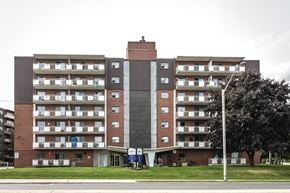 Hamilton apartment for rent - A large apartment building with a grey facade and balconies on each floor.