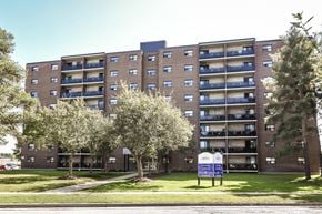 Kitchener apartment for rent - A large brick building with a blue sign in front of it.