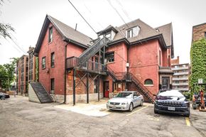 Hamilton apartment for rent - A red brick building with a black car parked in front.