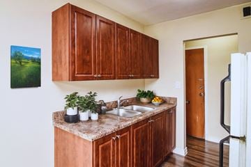 Hamilton apartment for rent - A kitchen with brown cabinets and a painting of a green field on the wall.