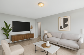 Hamilton apartment for rent - A living room with a grey couch, a white coffee table, and a large flat screen TV mounted on the wall.