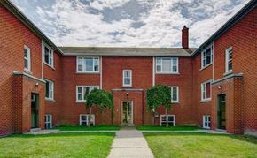 Kitchener apartment for rent - A red brick building with a green lawn in front.