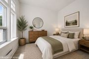 Kitchener apartment for rent - A bedroom with a large bed, a dresser, and a potted plant.