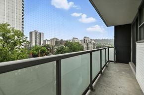 Hamilton apartment for rent - A balcony with a glass railing overlooks a cityscape.
