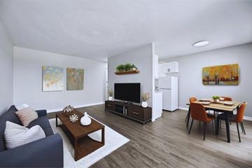 Hamilton apartment for rent - A living room with a blue couch, a coffee table, a TV, a dining table with chairs, and a painting on the wall.