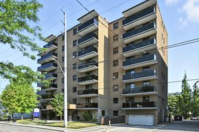 Hamilton apartment for rent - A large apartment building with balconies on the second floor and a garage door on the ground floor.
