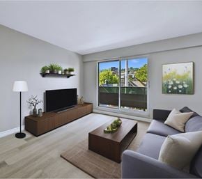 Hamilton apartment for rent - A living room with a grey couch, a wooden coffee table, a flat screen TV, and a large window with a view of the city.