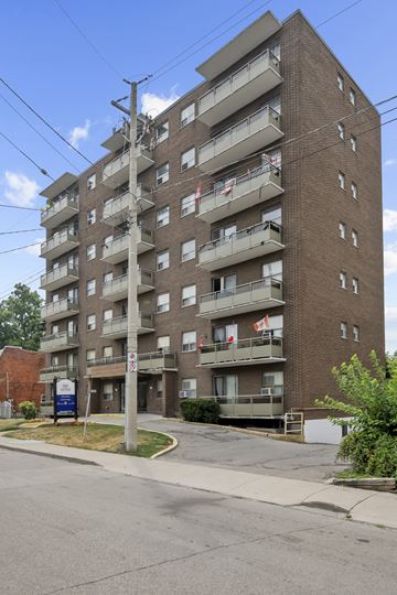 Hamilton apartment for rent - A tall apartment building with multiple balconies and flags hanging from the balconies.
