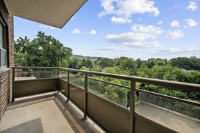Hamilton apartment for rent - A balcony with a metal railing overlooks a lush green landscape.