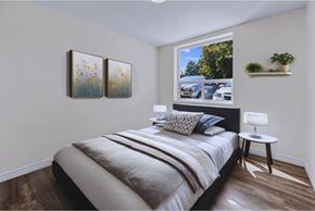 Stoney Creek apartment for rent - A bedroom with a bed, a nightstand, and a window with a view of a parking lot.