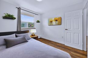 Hamilton apartment for rent - A bedroom with a bed, pillows, a lamp, and a painting on the wall.