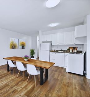 Hamilton apartment for rent - A kitchen with a table and chairs in the foreground and a refrigerator and cabinets in the background.