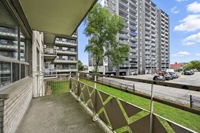 Hamilton apartment for rent - A view of a balcony with a metal railing and a building in the background.