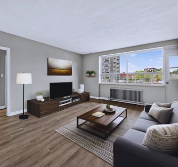 Hamilton apartment for rent - A living room with a grey couch, a wooden coffee table, and a television on a stand.