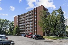 Stoney Creek apartment for rent - A large red brick building with a parking lot in front.