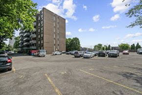 Hamilton apartment for rent - A parking lot with cars and a tall building in the background.