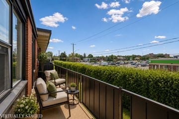 Kitchener apartment for rent - A balcony with a chair and table overlooking a parking lot.
