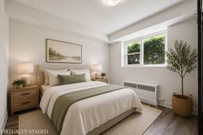 Kitchener apartment for rent - A bedroom with a large bed, a small tree, and a painting on the wall.