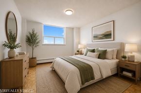 Kitchener apartment for rent - A bedroom with a large bed, a wooden dresser, and a window with a view of the sky.