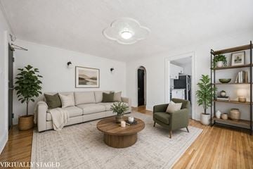 Kitchener apartment for rent - A living room with a white couch, a green armchair, a wooden coffee table, and a white rug.