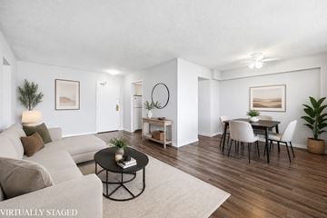 Hamilton apartment for rent - A living room with a white couch, a coffee table, and a dining table with chairs.