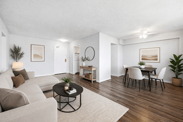 Hamilton apartment for rent - A living room with a grey sofa, a black coffee table, and a dining table with chairs.