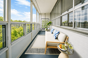 Hamilton apartment for rent - A white couch with a blue and white pillow is in front of a window with a view of trees.