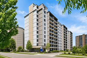Hamilton apartment for rent - A large, modern building with a beige facade and a blue sign in front.