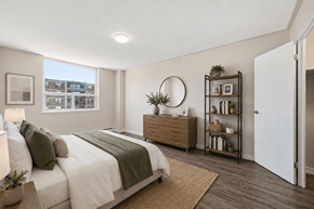 Hamilton apartment for rent - A bedroom with a large bed and a window overlooking a building.