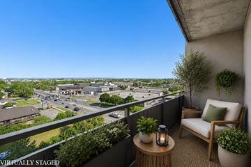 Hamilton apartment for rent - A balcony with a chair, table, and potted plants overlooks a city street.