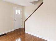 Cobourg apartment for rent - A white door is in a room with wooden floors and a staircase.