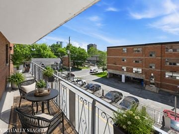 Hamilton apartment for rent - A balcony with a table and chairs overlooks a street.