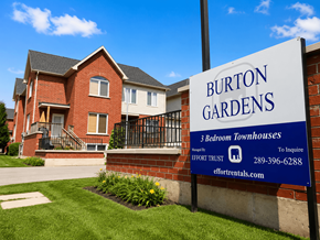 Hamilton apartment for rent - A sign for Burton Gardens 3 bedroom townhouses stands in front of a brick building.