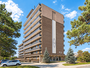 Hamilton apartment for rent - A large brown building with a clock on the side and a car parked in front.