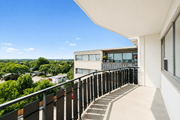 Hamilton apartment for rent - A balcony with a metal railing and steps leading to a building with a glass door.