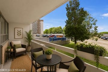 Hamilton apartment for rent - A balcony with a table and chairs overlooking a parking lot.