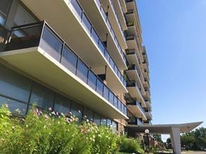 St. Catharines apartment for rent - A modern building with balconies and plants in front.