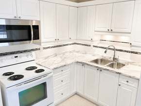 Dundas apartment for rent - A white kitchen with a stove, microwave, and sink.