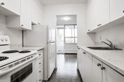 Hamilton apartment for rent - A white kitchen with a stove, refrigerator, and sink.