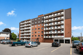 Hamilton apartment for rent - A large apartment building with a parking lot in front.