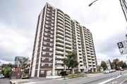 Kitchener apartment for rent - A tall apartment building with a parking lot in front.